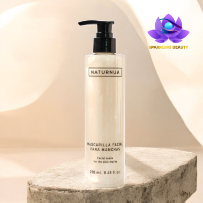 Frasco transparente de máscara facial NATURNUA para manchas com doseador preto em superfície de pedra clara.