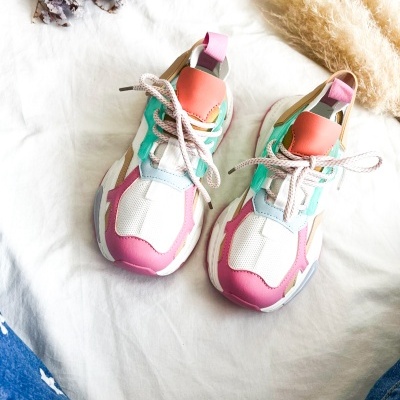 Sapatos desportivos coloridos sobre tecido branco com ramos secos ao fundo