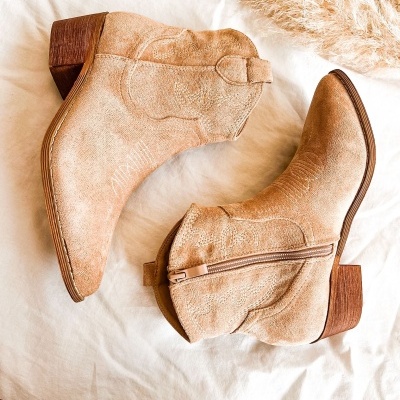 Botas de camurça bege com salto médio e fecho de correr lateral sobre tecido branco