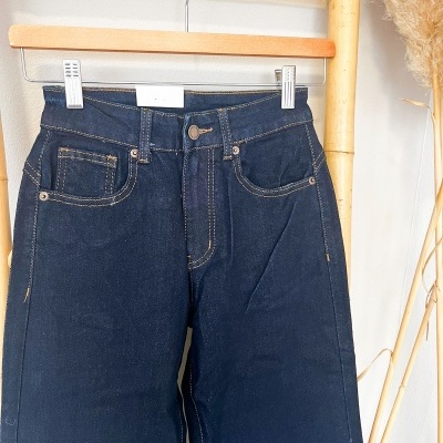 Calças de ganga azul escuro penduradas num cabide de madeira