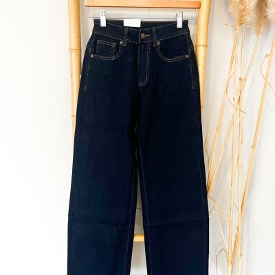 Calças de ganga largas azuis escuras penduradas numa estrutura de bambu