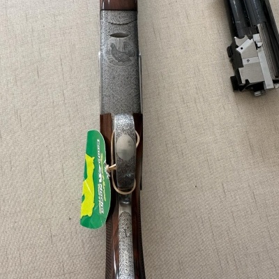 Arma de caça com detalhes em madeira e metal com etiqueta verde e amarela