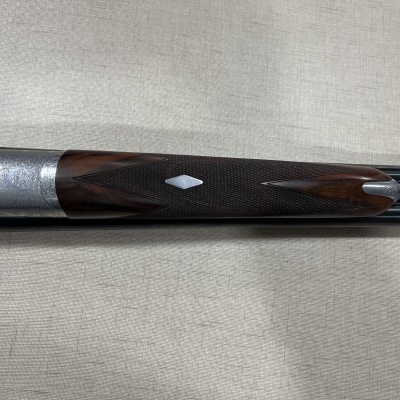 Parte de espingarda com madeira castanha, detalhes metálicos gravados e duas canas pretas