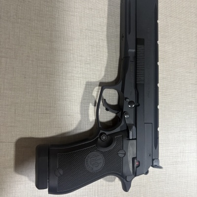 Pistola preta Beretta com punho texturizado e corpo metálico sobre fundo claro