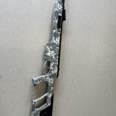 Espingarda de ar comprimido camuflada cinzenta e branca sobre fundo claro