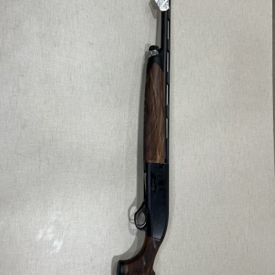 Espingarda de cano longo com partes em madeira castanha e metal preto, etiqueta branca no cano