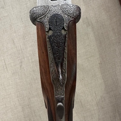 Arma de caça com cabo de madeira e detalhes metálicos gravados