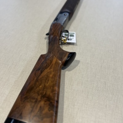 Espingarda de cano duplo com coronha em madeira castanha e metal preto sobre superfície bege