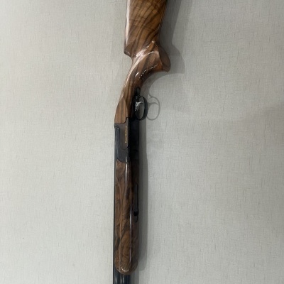 Espingarda de madeira e metal encostada a parede branca