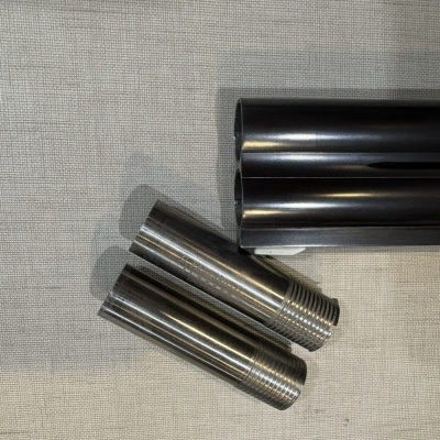 Peças cilíndricas metálicas com rosca e tubos pretos em tecido cinzento.