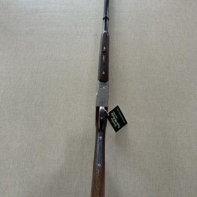 Rifle de caça com cabo em madeira e cano de metal colocado sobre superfície bege