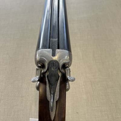 Arma de fogo de canos paralelos em metal azul escuro com cabo em madeira escura