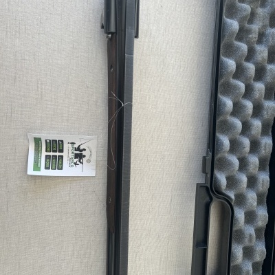 Cano de arma de fogo preta com etiqueta ao lado e estojo acolchoado cinzento