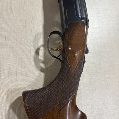 Coronha de espingarda em madeira castanha com gatilho dourado e metal preto