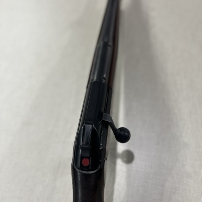 Espingarda de cano longo com coronha em madeira escura e acabamento metálico preto