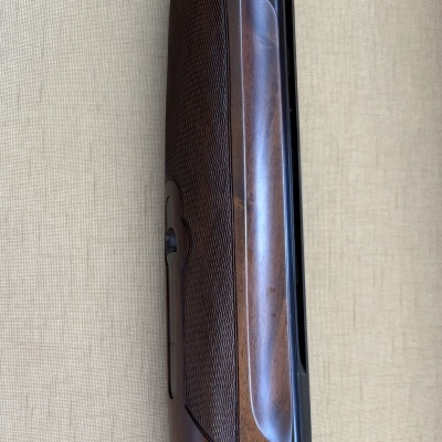 Espingarda em madeira castanha com textura estriada e detalhes em metal preto