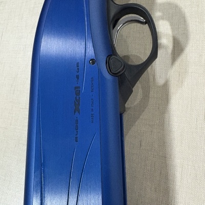 Parte lateral de arma de fogo azul com punho madeira e gatilho preto