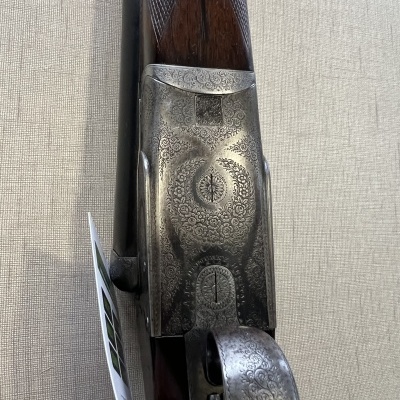 Detalhe de arma de fogo com metal gravado e madeira escura