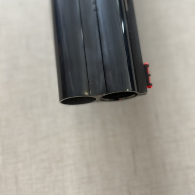 Ponta de cano preto de metal com duas aberturas cilíndricas e detalhe vermelho