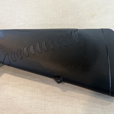 Coronha preta de arma de fogo com textura antiderrapante, em superfície bege