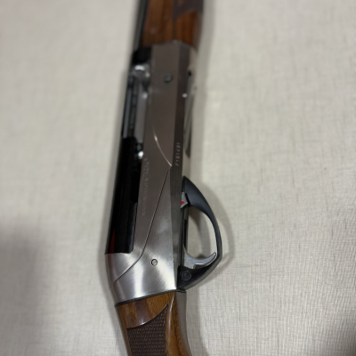 Espingarda com madeira castanha e partes metálicas prateadas e pretas