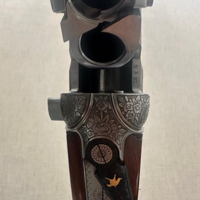 Espingarda de canos duplos com gravações florais em metal escuro e madeira castanha