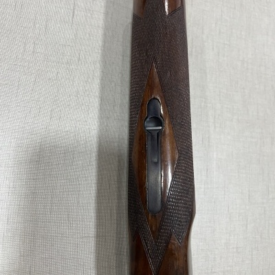 Parte de arma com empunhadura em madeira texturada e metal preto