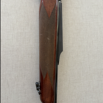 Coronha de espingarda em madeira castanha com padrão geométrico e cano metálico preto