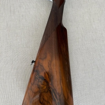 Coronha de espingarda em madeira castanha com detalhes em metal prateado e etiqueta pendurada