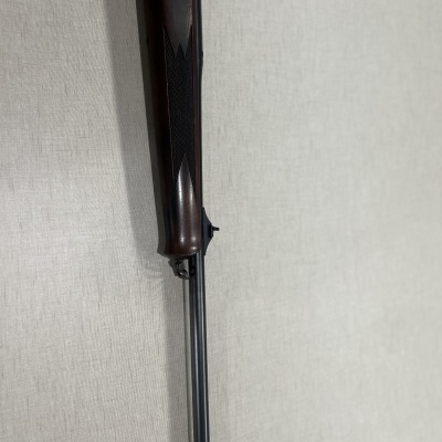 Espingarda com coronha de madeira e cano metálico sobre fundo claro