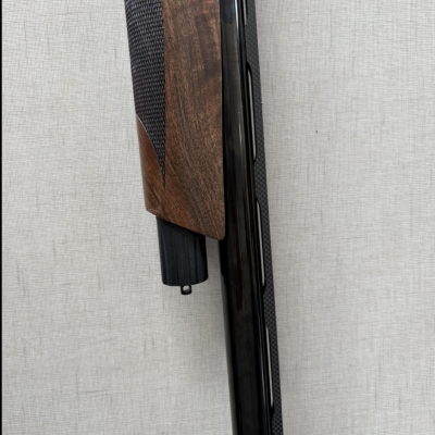 Parte de arma de fogo com empunhadura de madeira castanha e cano metálico preto