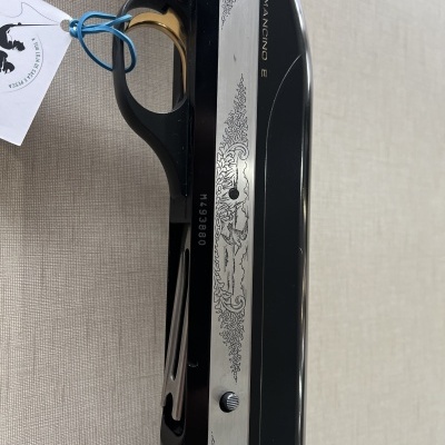 Arma de fogo com madeira e metal preto com detalhes gravados e etiqueta pendurada.