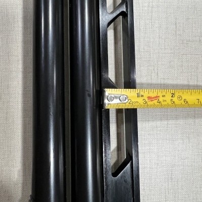 Objeto metálico preto com cilindros e fita métrica sobre tecido cinza