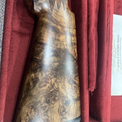 Parte traseira de coronha de arma de madeira em tecido vermelho com etiqueta branca