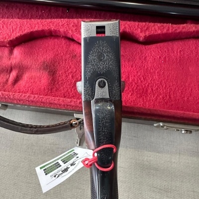 Espingarda em caixa vermelha com coronha de madeira e detalhes metálicos