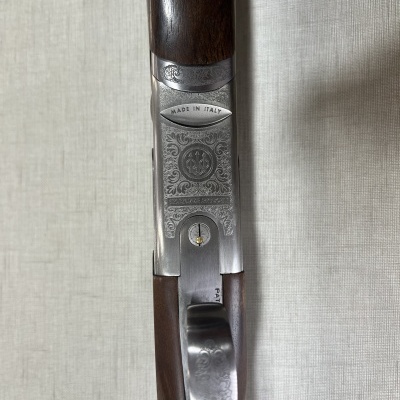 Espingarda com madeira castanha e metal prateado gravado, inscrição MADE IN ITALY