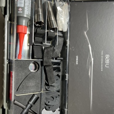 Conjunto de acessórios para instrumentos de corda organizados numa caixa preta com texto USS8 THE OBSERVER