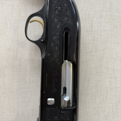 Parte do corpo de uma espingarda preta com gravuras e punho de madeira