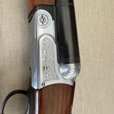 Parte de arma com metal prateado gravado e madeira castanha