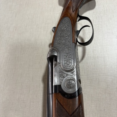 Arma de caça com cano duplo e acabamento em madeira e metal gravado
