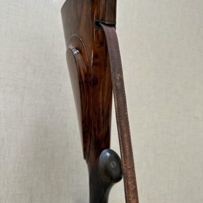 Espingarda com coronha de madeira castanha e alça de couro