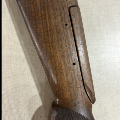 Coronha de madeira castanho-escura para espingarda com acabamento polido e detalhes emborrachados.