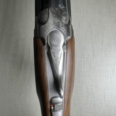 Parte superior de arma de fogo com madeira escura e metal gravado prateado