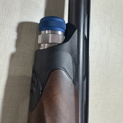 Coronha de madeira de arma com metal preto e azul junto a uma superfície clara.