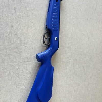 Espingarda azul com gatilho preto apoiada em fundo cinza