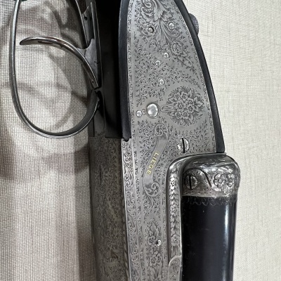 Espingarda metálica gravada com detalhes florais e empunhadura preta