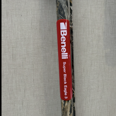 Espingarda de caça camuflada com etiqueta Benelli vermelha