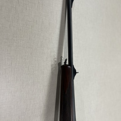 Espingarda de cano longo com madeira castanha pendurada em parede azul claro