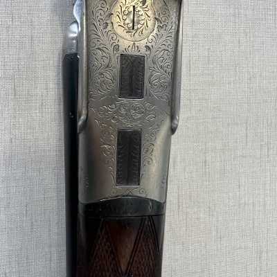 Espingarda com cabo em madeira escura e metal gravado com padrões florais e geométricos