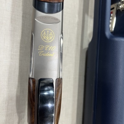 Espingarda de madeira castanha com marcas douradas em metal cinza e estojo azul